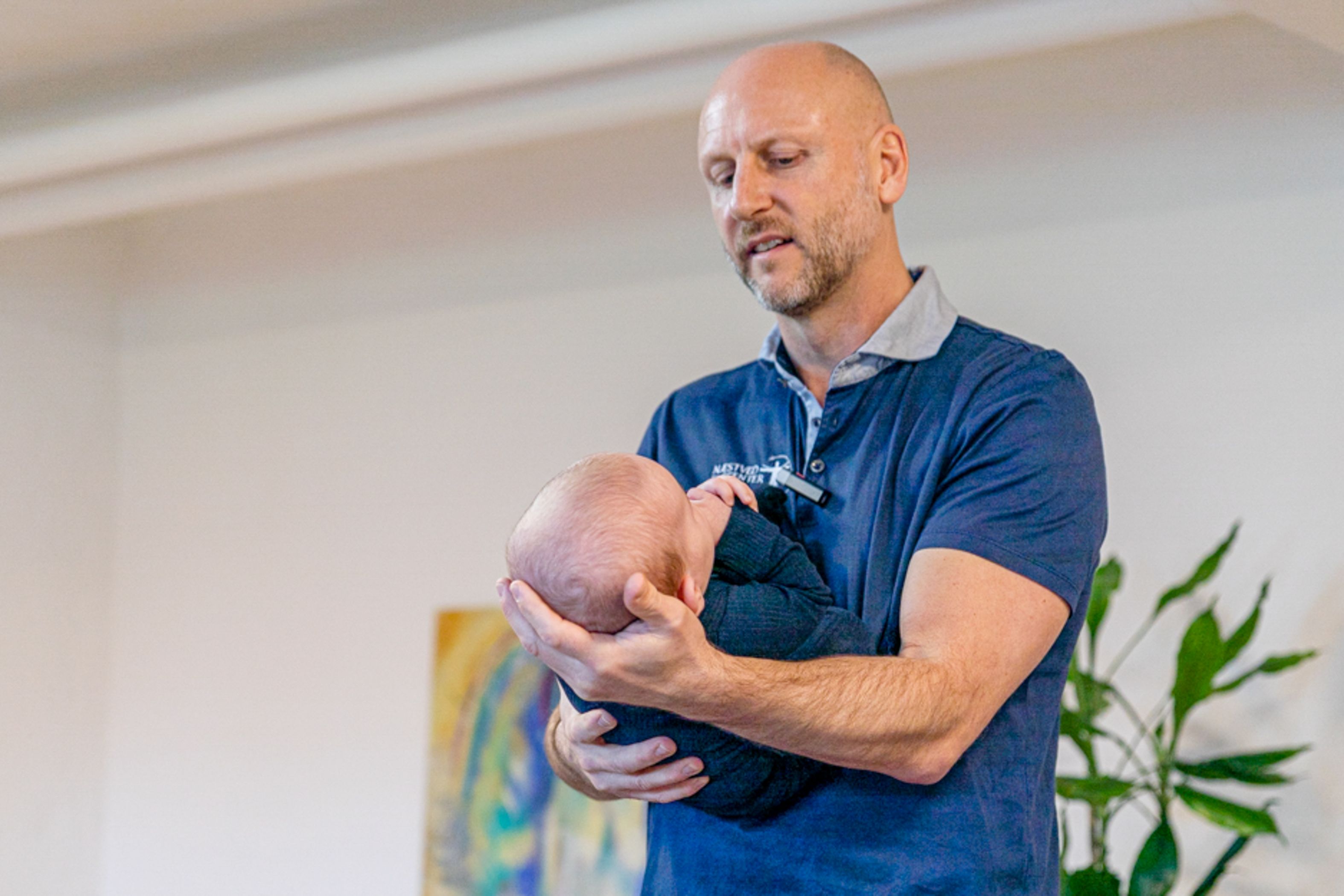 Hans Andersen har samlet flere sundhedsfag i sit rygcenter. Selv er han ofte i aktion - som her med hjælp til en baby. Foto: Næstved Rygcenter