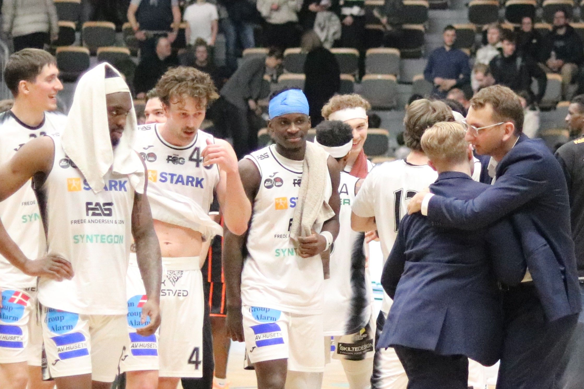 Chefcoach David Pavlakovich og assistent Adam Kaplan får sig en sejrskrammer, mens spillerne ser kærligt til. Foto: John Ringstrøm