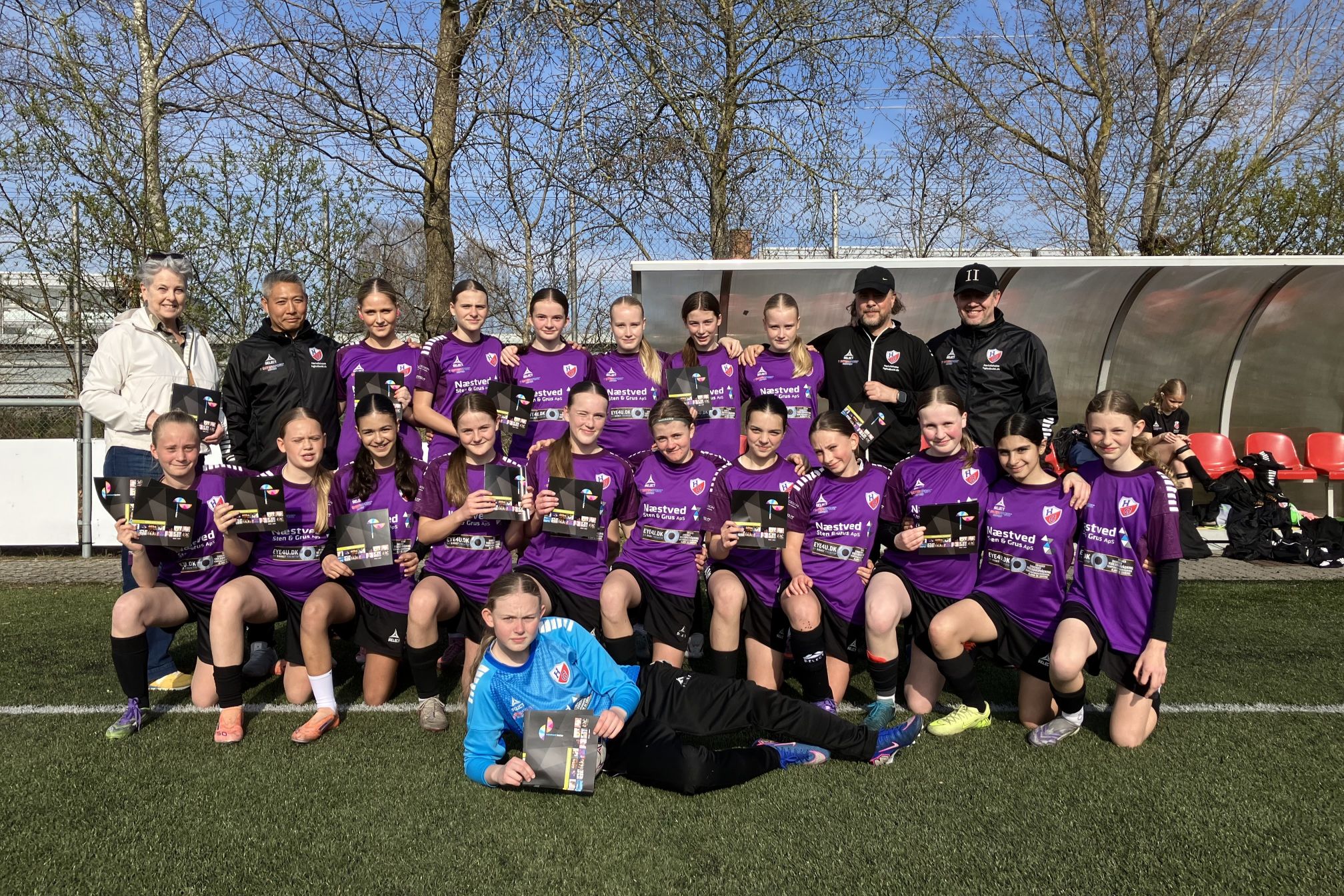 Pigeholdet HGQ U 14 Elite med Næstved Teaters gentegningsbrochurer i hænderne flankeret af kasserer Bettina Schou fra Næstved Teater, assistenttræner Christian Madsen, cheftræner Kim Terp og hjælpetræner Allan Jonsson. Foto: Presse