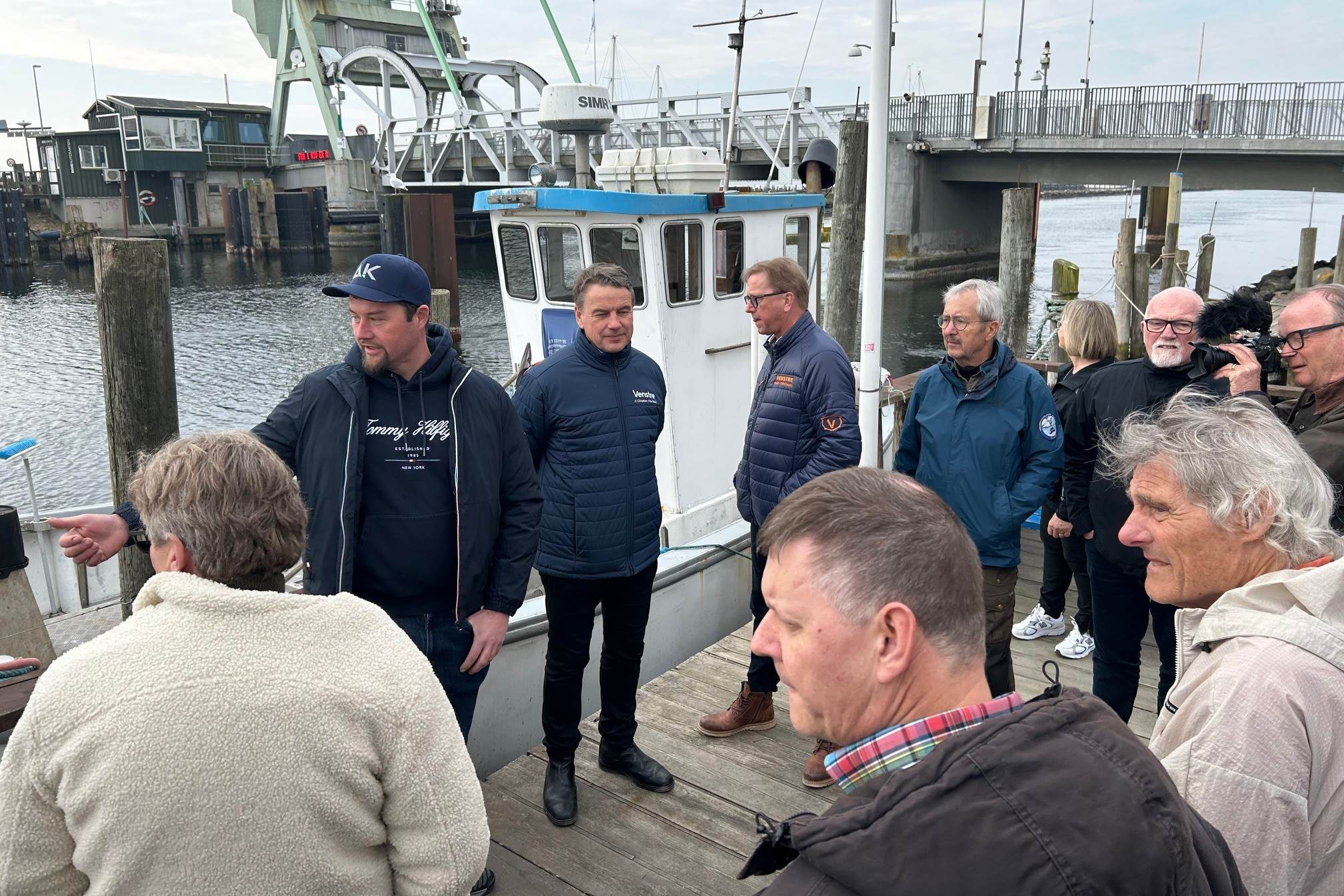 Thomas Ditlevsen (med kasket) fortæller om fiskernes situation i Karrebæksminde, mens Christian Friis Bach står ved siden af og lytter. Foto: John Ringstrøm