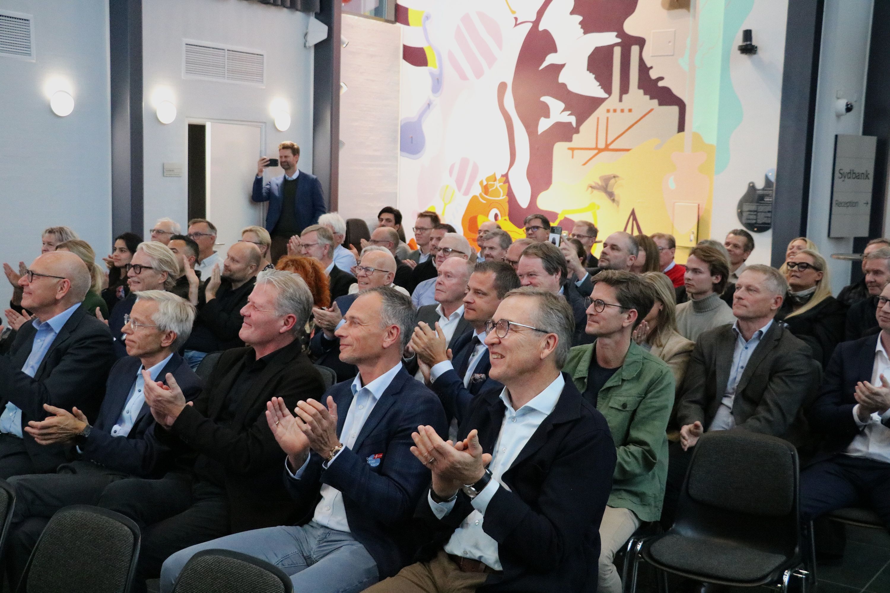 Der er klapsalver til vinderne. Også fra nummer to, Dan Group Alarm, der her sidder på forreste række med Claus Rasmussen som nummer to fra højre og Jens Vintersborg, der er driftschef, som nummer tre. Foto: John Ringstrøm