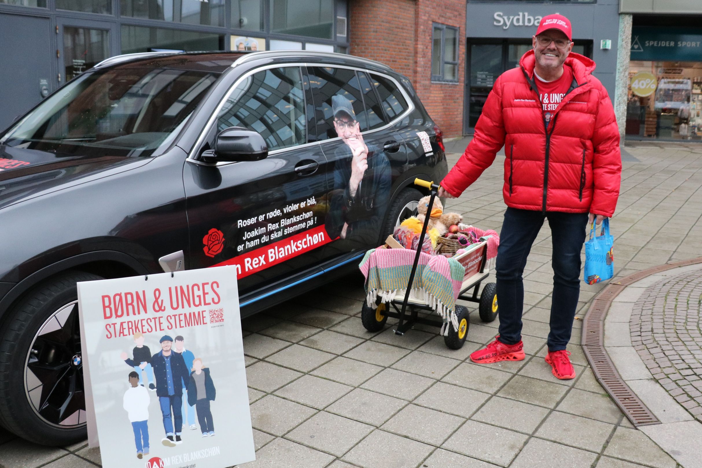 Man kan ikke undgå at se Joakim Rex Blankschøn, når han kommer rundt med sin trækvogn, bil, plakat og røde outfit. Plakaten er i øvrigt kreeret af Siff Kongsted, der er kunstneren bag Næstvedkalenderen. Foto: John Ringstrøm 