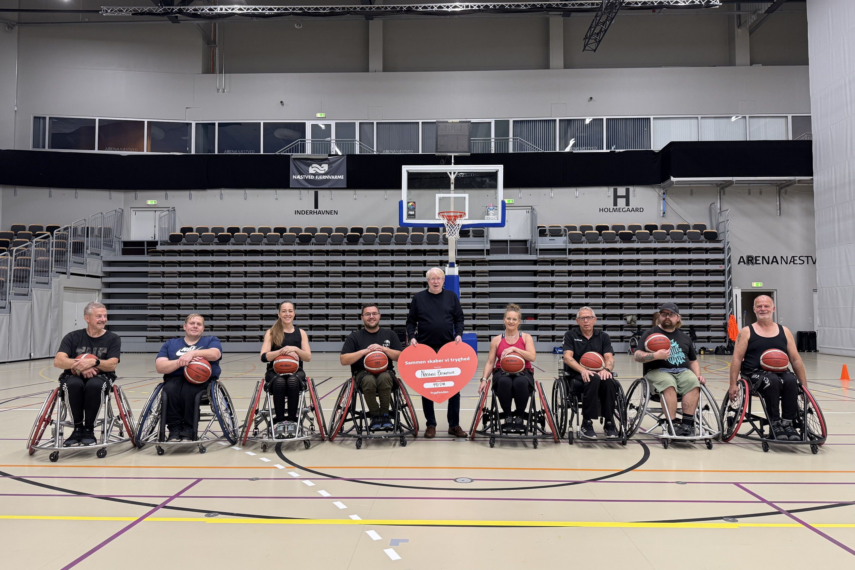 Næstved Basketball - hele basketholdet med Jørn Rise Andersen fra TrygFonden med checken. Foto: Næstved Kørestolbasket