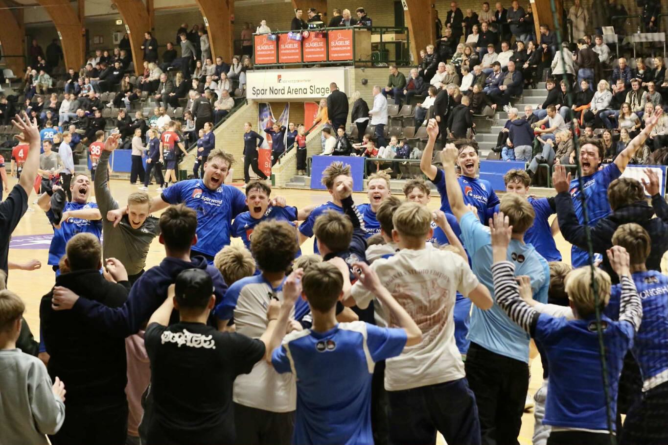 Næstved-spillerne jubler sammen med de tilrejsende fans, da oprykningen er i hus. Foto: Claus Pych
